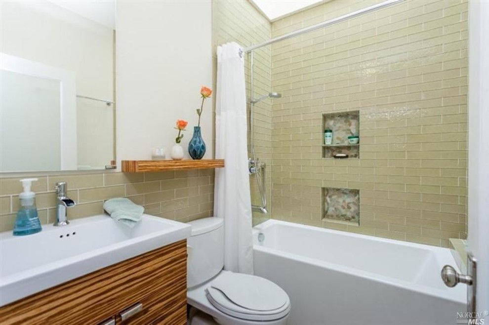 Inspiration for a medium sized classic shower room bathroom in San Francisco with flat-panel cabinets, medium wood cabinets, a built-in bath, a shower/bath combination, a two-piece toilet, beige tiles, beige walls and a built-in sink.