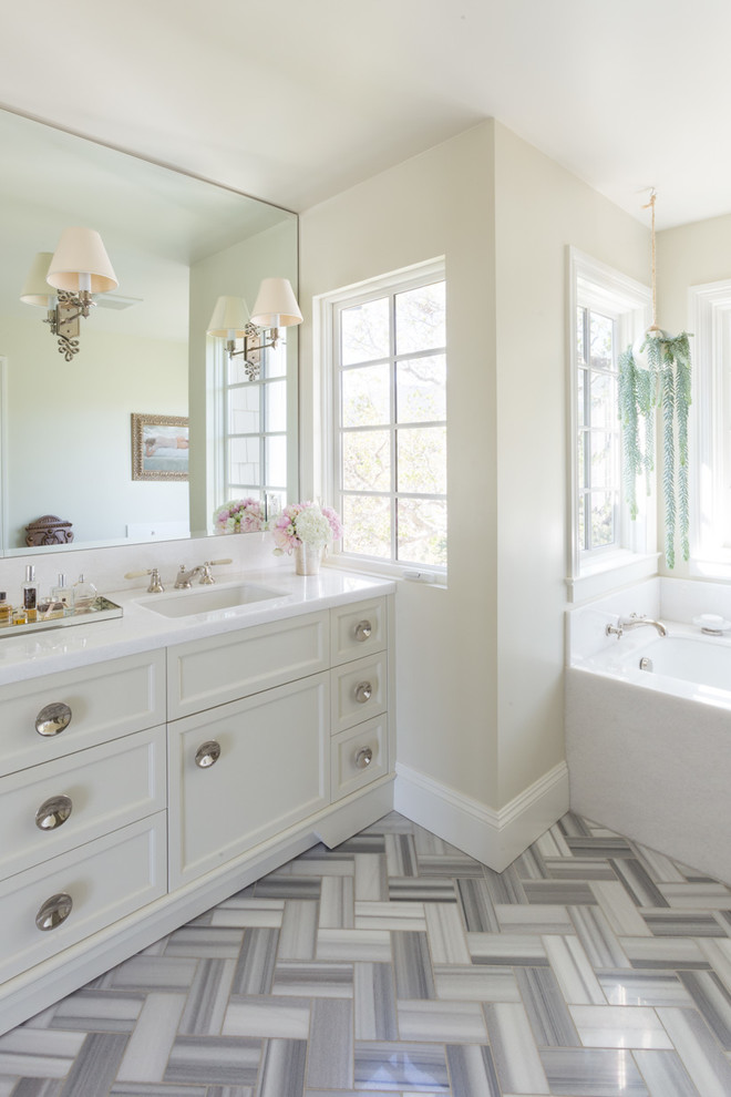 Foto di una stanza da bagno classica con lavabo sottopiano, ante con riquadro incassato, ante bianche, vasca sottopiano e pareti beige