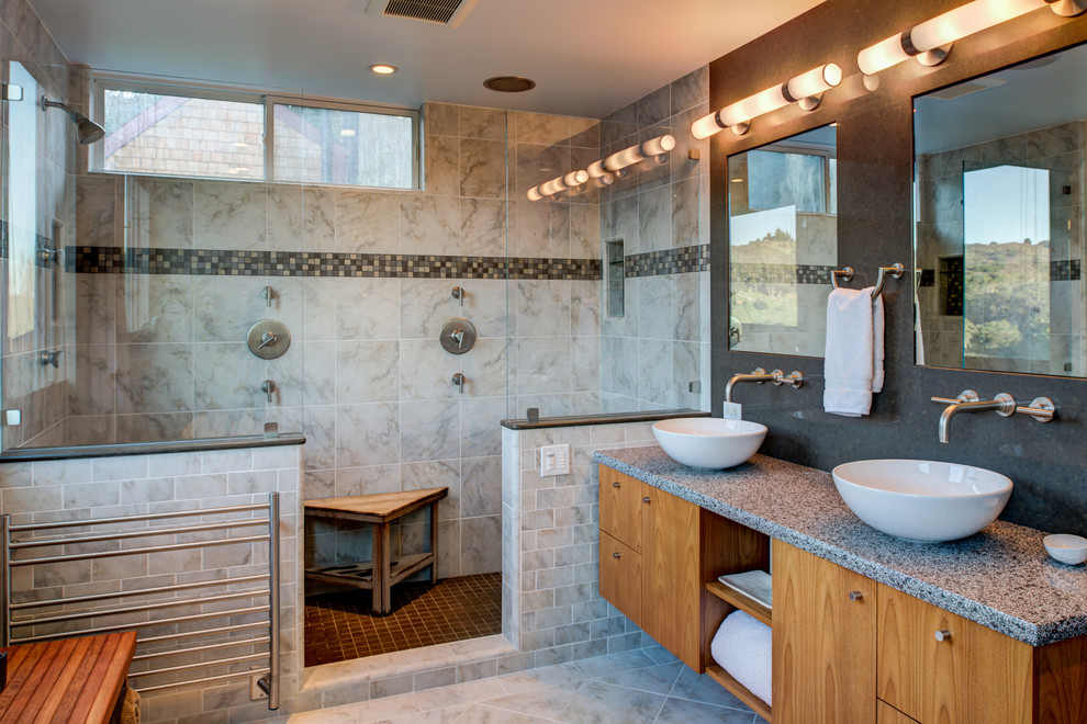 Inspiration pour une salle de bain principale design en bois brun de taille moyenne avec une vasque, un placard à porte plane, un plan de toilette en verre recyclé, un carrelage gris, un carrelage de pierre, un sol en marbre, une douche double, un mur gris et une fenêtre.