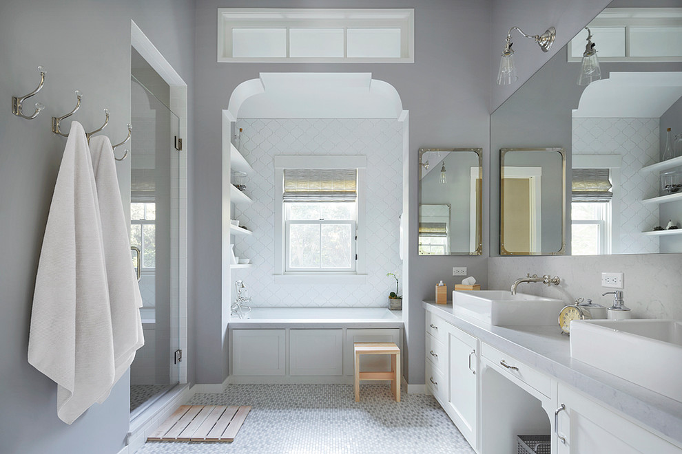 Inredning av ett lantligt badrum, med ett fristående handfat, skåp i shakerstil, vita skåp, en dusch i en alkov, vit kakel, grå väggar och mosaikgolv