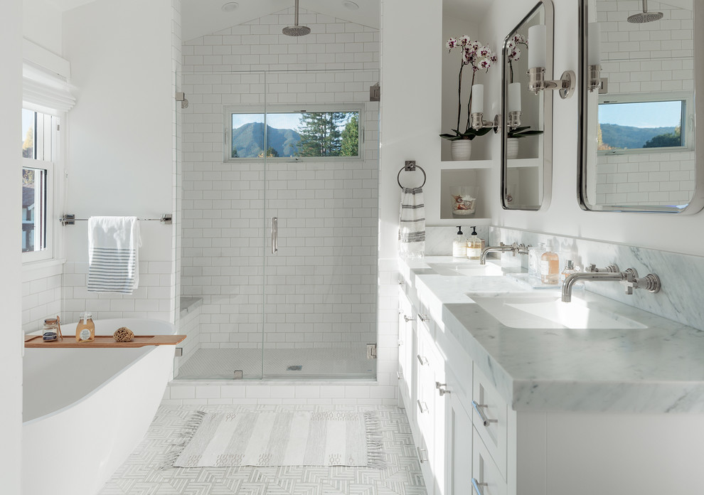 Traditional ensuite bathroom in San Francisco with shaker cabinets, white cabinets, a freestanding bath, an alcove shower, white tiles, metro tiles, white walls, a submerged sink, grey floors and a hinged door.