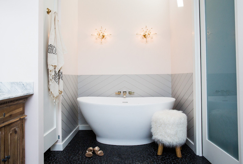 Klassisk inredning av ett badrum, med luckor med upphöjd panel, bruna skåp, ett fristående badkar, klinkergolv i småsten och svart golv