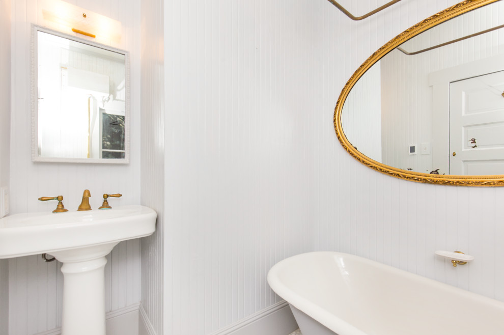 Foto på ett litet rustikt badrum, med ett badkar med tassar, en dusch/badkar-kombination, en toalettstol med separat cisternkåpa, vita väggar och ett piedestal handfat