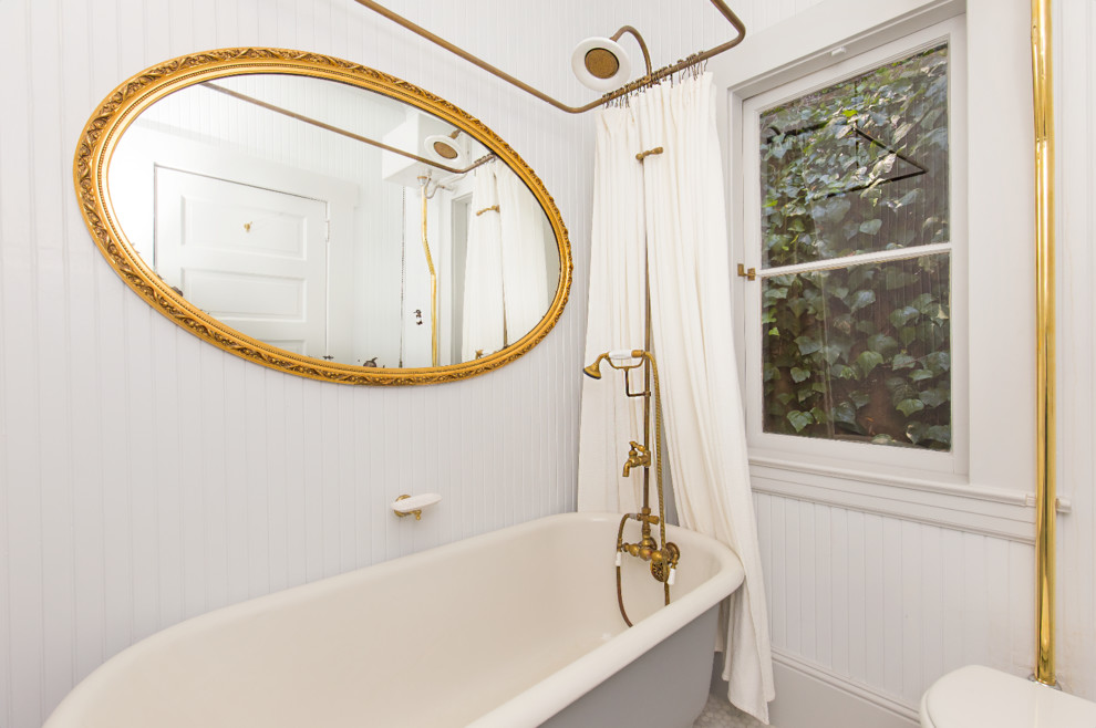 Bild på ett litet rustikt badrum, med ett badkar med tassar, en dusch/badkar-kombination, en toalettstol med separat cisternkåpa, vita väggar och ett piedestal handfat