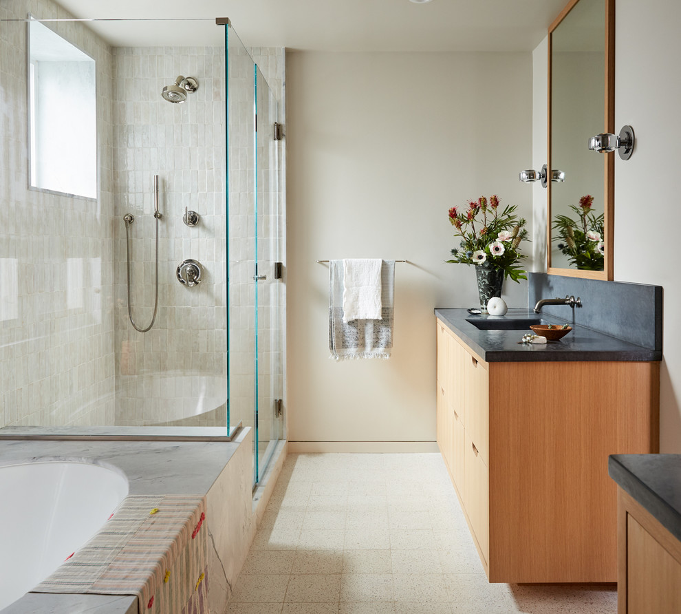 Aménagement d'une salle de bain scandinave en bois clair avec un placard à porte plane, un sol en carrelage de céramique, une cabine de douche à porte battante, un plan de toilette gris, une baignoire encastrée, un carrelage beige, un mur beige, un lavabo encastré et un sol beige.