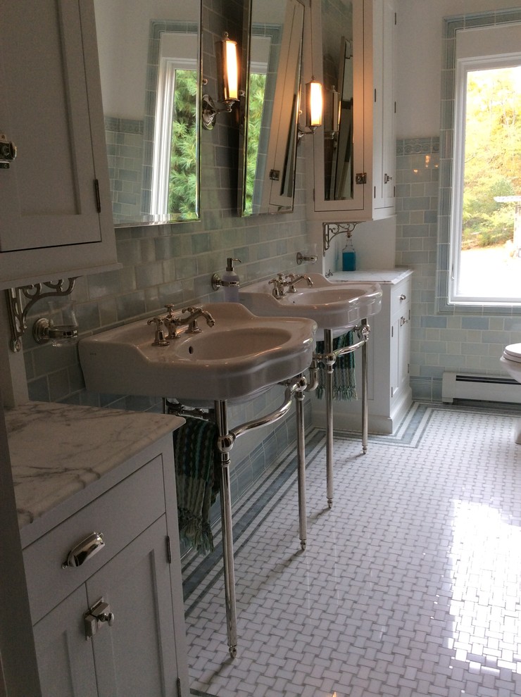 Elegant white tile and mosaic tile mosaic tile floor bathroom photo in New York with a pedestal sink, furniture-like cabinets, white cabinets, marble countertops and white walls