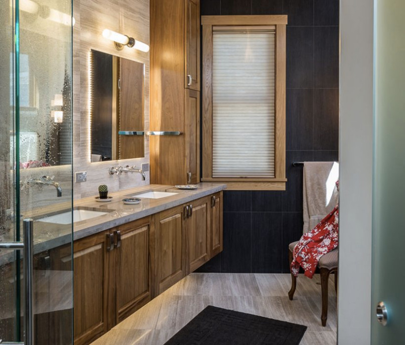 Exemple d'une salle de bain montagne en bois brun de taille moyenne avec un placard avec porte à panneau surélevé, un carrelage noir, des carreaux de porcelaine, un mur noir, un sol en carrelage de porcelaine, un lavabo encastré, un plan de toilette en surface solide et un sol beige.