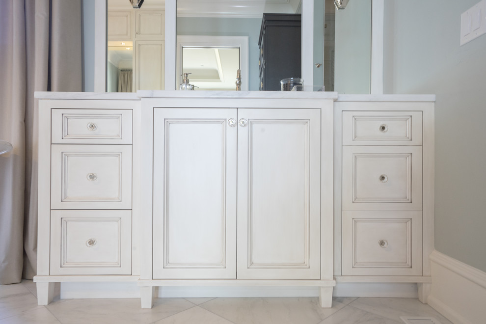 Bild på ett vintage vit vitt en-suite badrum, med luckor med profilerade fronter, vita skåp, ett fristående badkar, vit kakel, blå väggar, ett undermonterad handfat, marmorbänkskiva, grått golv och dusch med gångjärnsdörr