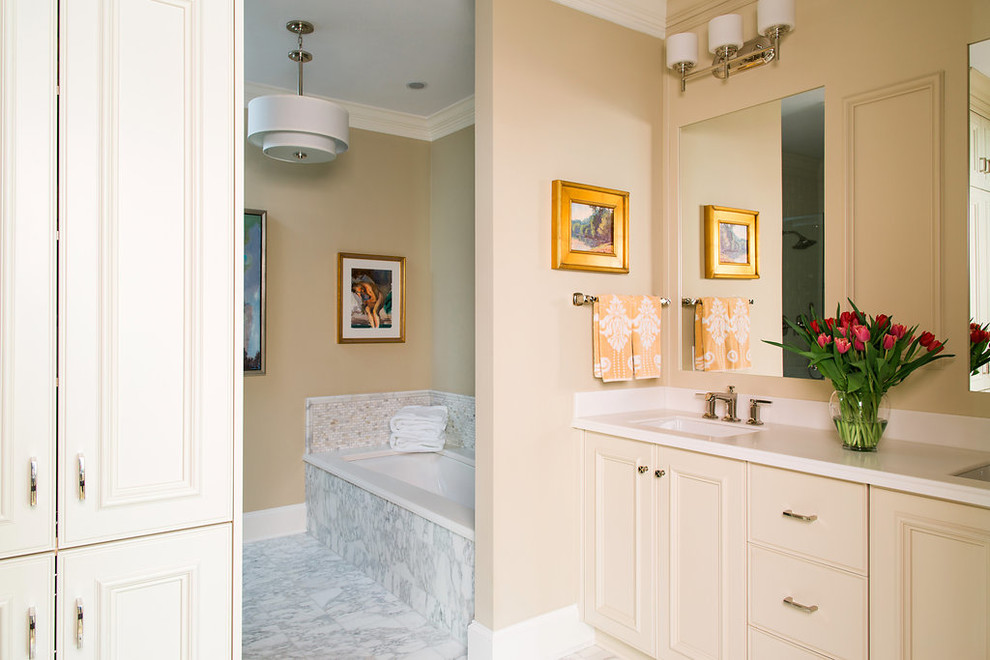 Foto på ett mellanstort vintage en-suite badrum, med luckor med infälld panel, grå skåp, ett undermonterat badkar, beige kakel, stickkakel, beige väggar, marmorgolv och bänkskiva i akrylsten