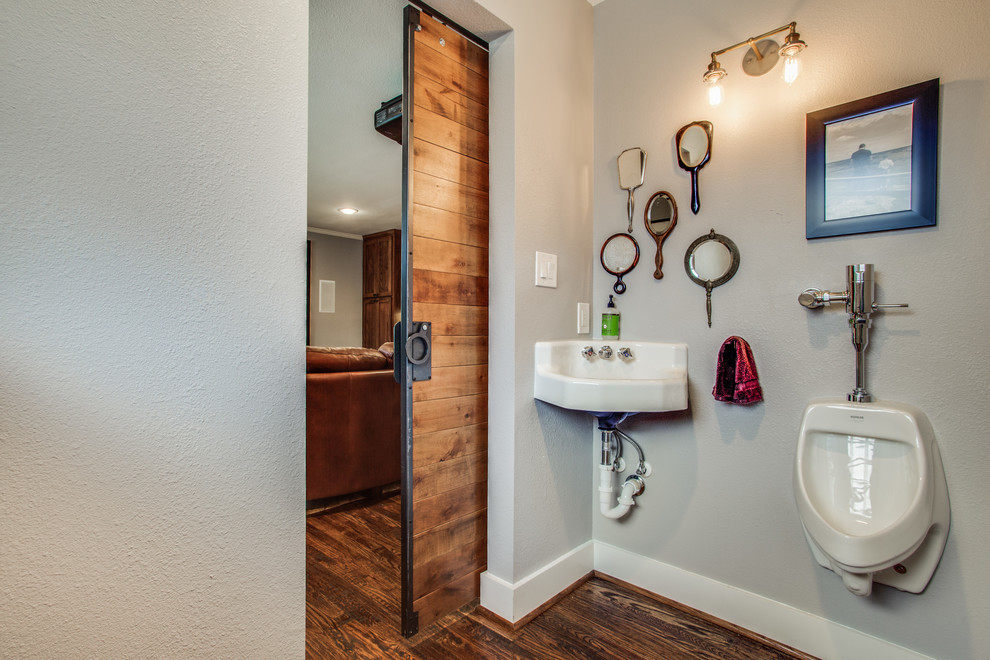 This is an example of a medium sized bohemian bathroom in Dallas with an urinal, grey walls, medium hardwood flooring, a wall-mounted sink and brown floors.