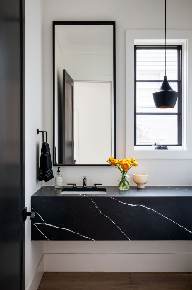Example of a trendy medium tone wood floor, brown floor and single-sink bathroom design in DC Metro with black cabinets, white walls, an undermount sink, black countertops and a floating vanity