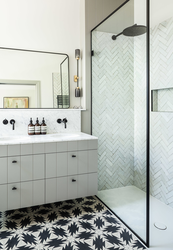 Стильный дизайн: ванная комната в современном стиле с серыми фасадами, угловым душем, серой плиткой, белой плиткой, бежевыми стенами, душевой кабиной, врезной раковиной, разноцветным полом и серой столешницей - последний тренд