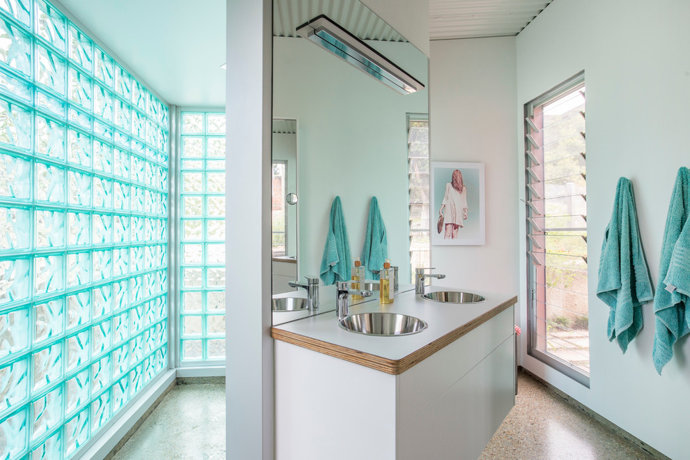 Imagen de cuarto de baño principal rústico de tamaño medio con armarios con paneles lisos, puertas de armario de madera clara, paredes azules, suelo de cemento, lavabo encastrado y encimera de madera