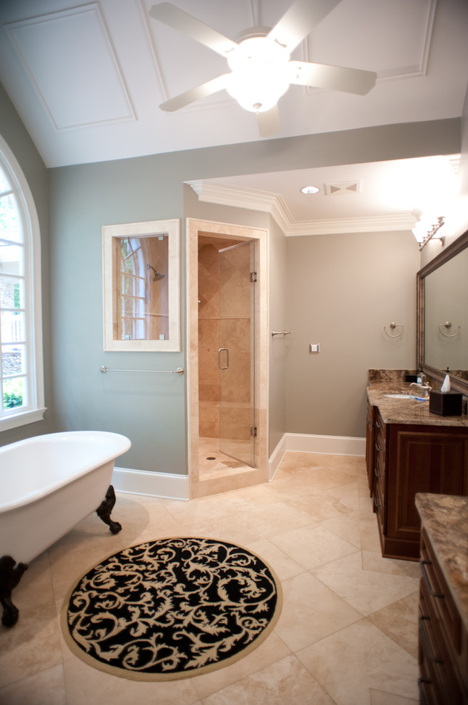 Пример оригинального дизайна: большая главная ванная комната в классическом стиле с плоскими фасадами, темными деревянными фасадами, столешницей из гранита, ванной на ножках, бежевой плиткой, каменной плиткой, синими стенами и полом из травертина