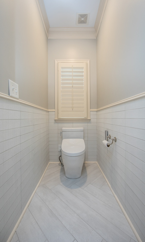 Example of a large country white tile and ceramic tile porcelain tile, gray floor and wainscoting powder room design in Atlanta with flat-panel cabinets, white cabinets, a one-piece toilet, gray walls, an undermount sink, quartz countertops, white countertops and a built-in vanity