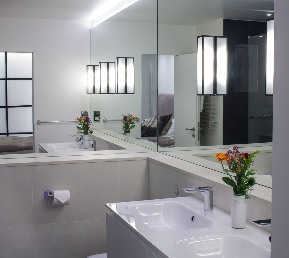 Ispirazione per una stanza da bagno padronale minimal di medie dimensioni con lavabo integrato, ante bianche, top in superficie solida, WC sospeso, piastrelle in ceramica e pavimento con piastrelle in ceramica