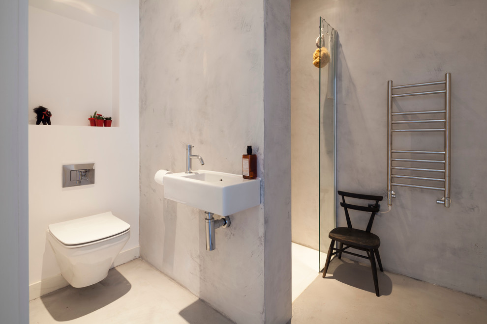 Idee per una stanza da bagno con doccia contemporanea di medie dimensioni con lavabo sospeso, doccia a filo pavimento, WC sospeso, pareti grigie e pavimento in cemento