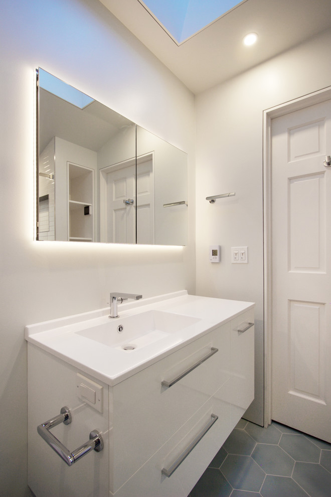 Идея дизайна: ванная комната среднего размера в стиле модернизм с белыми фасадами, душем в нише, инсталляцией, белой плиткой, плиткой кабанчик, белыми стенами, полом из цементной плитки, душевой кабиной, монолитной раковиной, столешницей из искусственного камня, синим полом и душем с раздвижными дверями