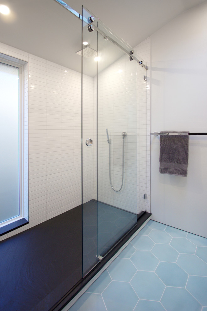 他の地域にある高級な中くらいなモダンスタイルのおしゃれなバスルーム (浴槽なし) (白いキャビネット、アルコーブ型シャワー、壁掛け式トイレ、白いタイル、サブウェイタイル、白い壁、セメントタイルの床、一体型シンク、人工大理石カウンター、青い床、引戸のシャワー) の写真