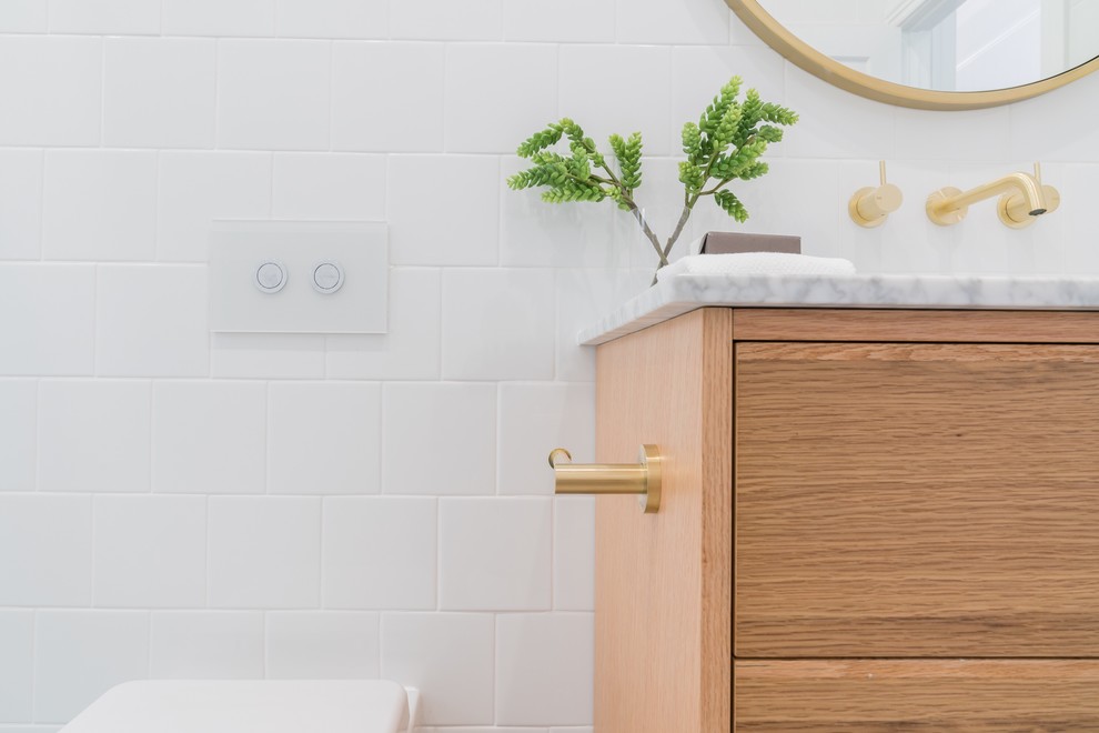Источник вдохновения для домашнего уюта: ванная комната среднего размера в стиле модернизм с фасадами островного типа, светлыми деревянными фасадами, отдельно стоящей ванной, открытым душем, унитазом-моноблоком, белой плиткой, керамической плиткой, белыми стенами, полом из ламината, душевой кабиной, врезной раковиной, мраморной столешницей, разноцветным полом, открытым душем и белой столешницей