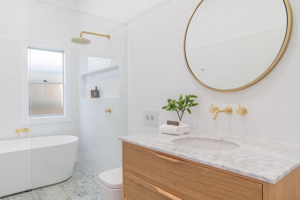 Inspiration for a medium sized modern shower room bathroom in Brisbane with freestanding cabinets, light wood cabinets, a freestanding bath, a walk-in shower, a one-piece toilet, white tiles, ceramic tiles, white walls, laminate floors, a submerged sink, marble worktops, multi-coloured floors, an open shower and white worktops.