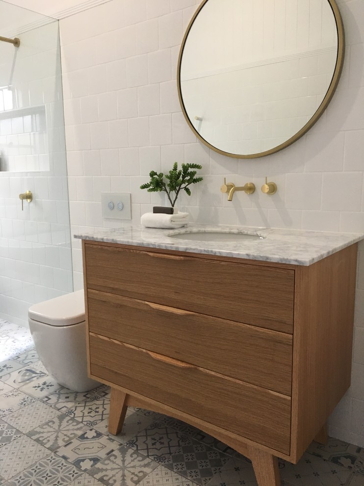 Mid-sized minimalist 3/4 white tile and ceramic tile laminate floor and multicolored floor bathroom photo in Brisbane with furniture-like cabinets, light wood cabinets, a one-piece toilet, white walls, an undermount sink, marble countertops and white countertops