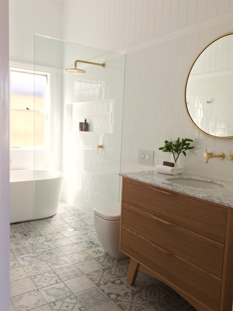 Idéer för mellanstora funkis vitt badrum med dusch, med möbel-liknande, skåp i ljust trä, ett fristående badkar, en öppen dusch, en toalettstol med hel cisternkåpa, vit kakel, keramikplattor, vita väggar, laminatgolv, ett undermonterad handfat, marmorbänkskiva, flerfärgat golv och med dusch som är öppen