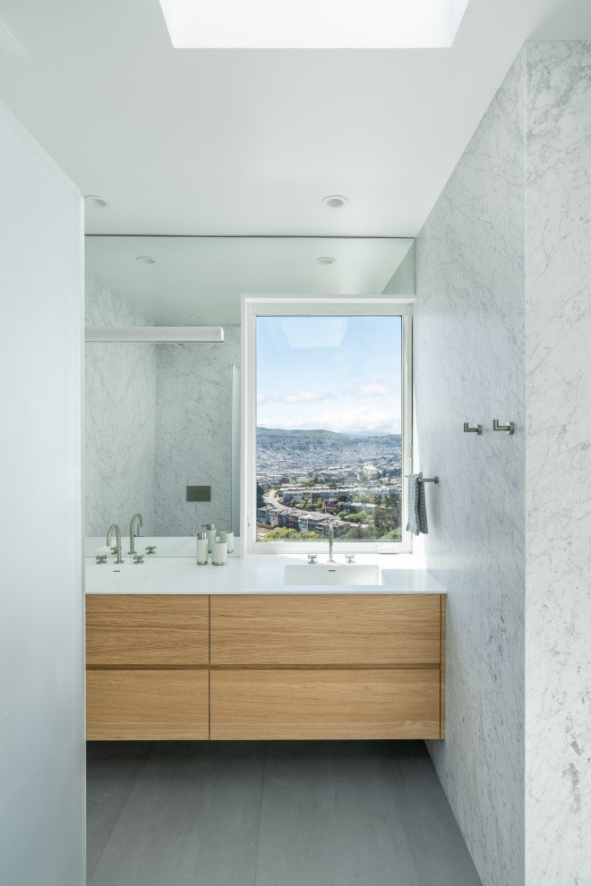 Photo of a medium sized modern family bathroom in San Francisco with flat-panel cabinets, white cabinets, an alcove bath, a shower/bath combination, a wall mounted toilet, blue tiles, cement tiles, white walls, cement flooring, an integrated sink, solid surface worktops, blue floors, white worktops, a wall niche, double sinks and a built in vanity unit.