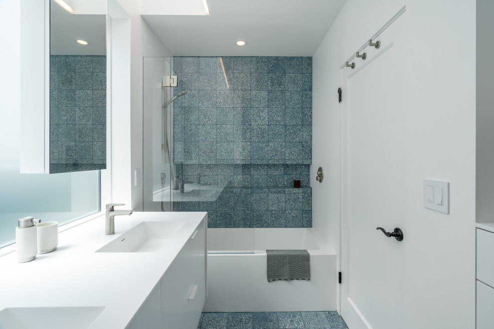 Пример оригинального дизайна: детская ванная комната среднего размера в стиле модернизм с плоскими фасадами, белыми фасадами, ванной в нише, душем над ванной, инсталляцией, синей плиткой, цементной плиткой, белыми стенами, полом из цементной плитки, монолитной раковиной, столешницей из искусственного камня, синим полом, белой столешницей, нишей, тумбой под две раковины и встроенной тумбой