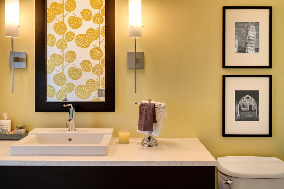 Cette image montre une salle de bain urbaine avec un mur jaune et sol en béton ciré.