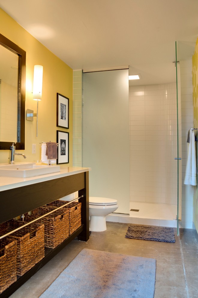 Idée de décoration pour une salle de bain urbaine avec un mur jaune et sol en béton ciré.
