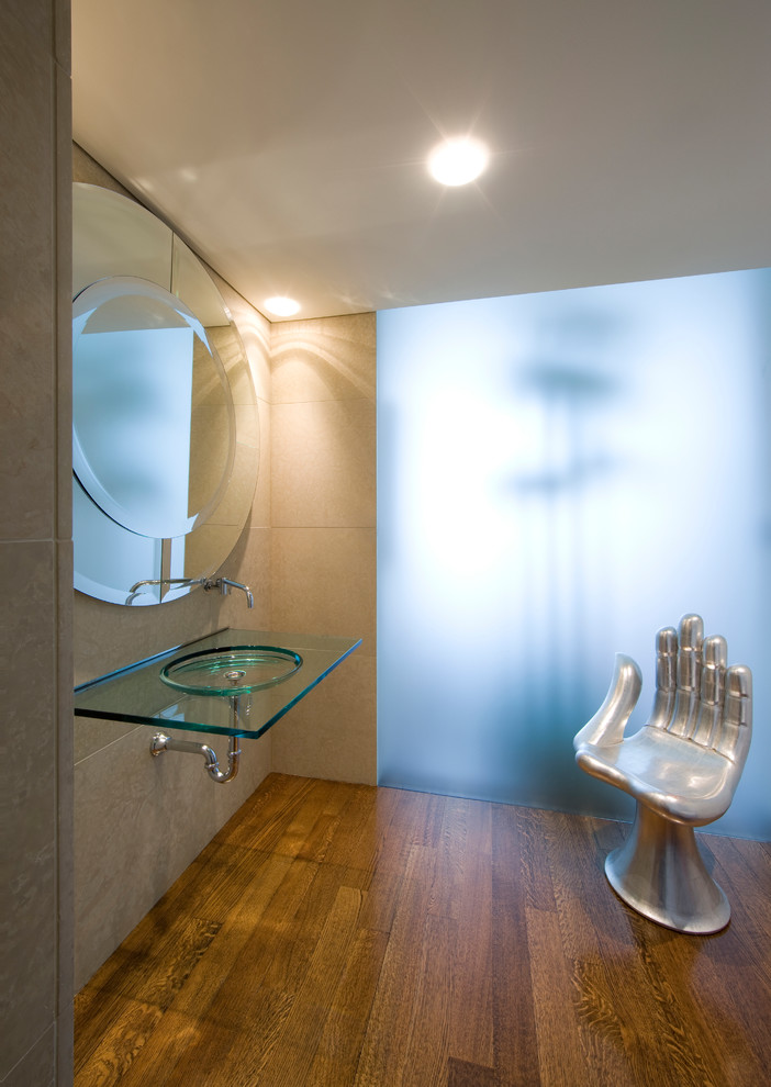 Идея дизайна: ванная комната в современном стиле с подвесной раковиной, стеклянной столешницей, каменной плиткой, темным паркетным полом и бежевыми стенами