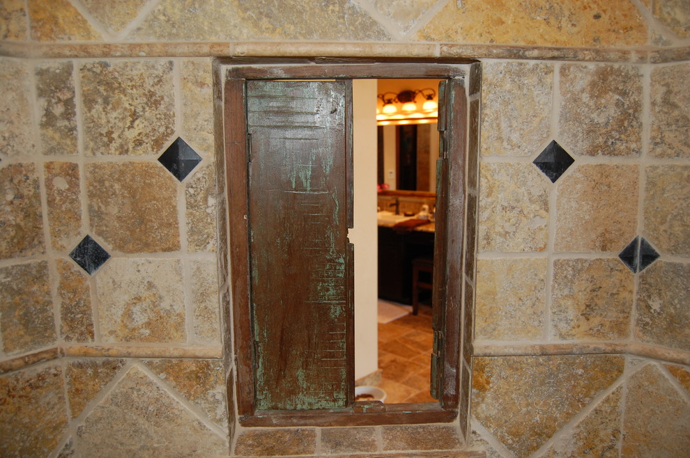 Пример оригинального дизайна: главная ванная комната в средиземноморском стиле с фасадами с выступающей филенкой, темными деревянными фасадами, столешницей из гранита, бежевыми стенами и полом из травертина