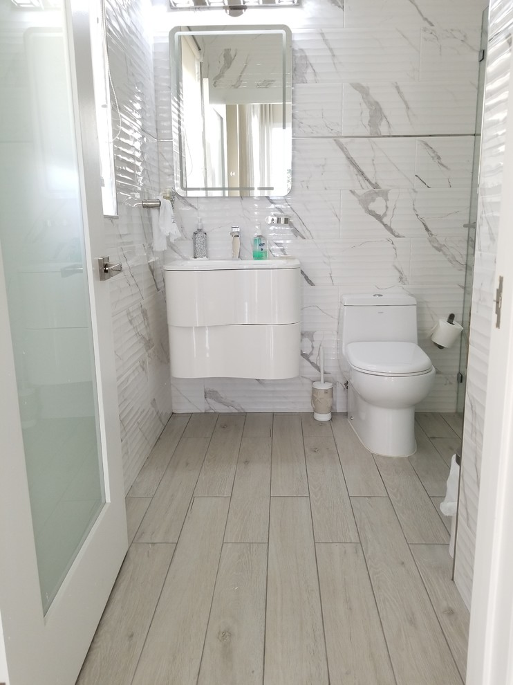 Example of a small minimalist kids' white tile and porcelain tile porcelain tile and beige floor bathroom design in Miami with raised-panel cabinets, white cabinets, a one-piece toilet, white walls, a wall-mount sink, quartz countertops and a hinged shower door