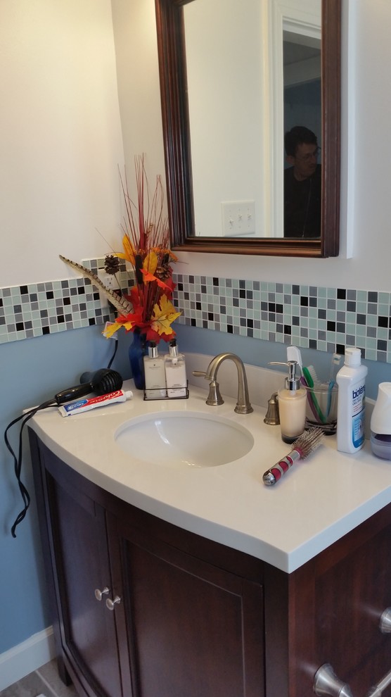 Eklektisk inredning av ett litet badrum med dusch, med skåp i shakerstil, skåp i mellenmörkt trä, en dusch i en alkov, en toalettstol med separat cisternkåpa, flerfärgad kakel, glaskakel, blå väggar, klinkergolv i porslin, ett undermonterad handfat och bänkskiva i kvarts