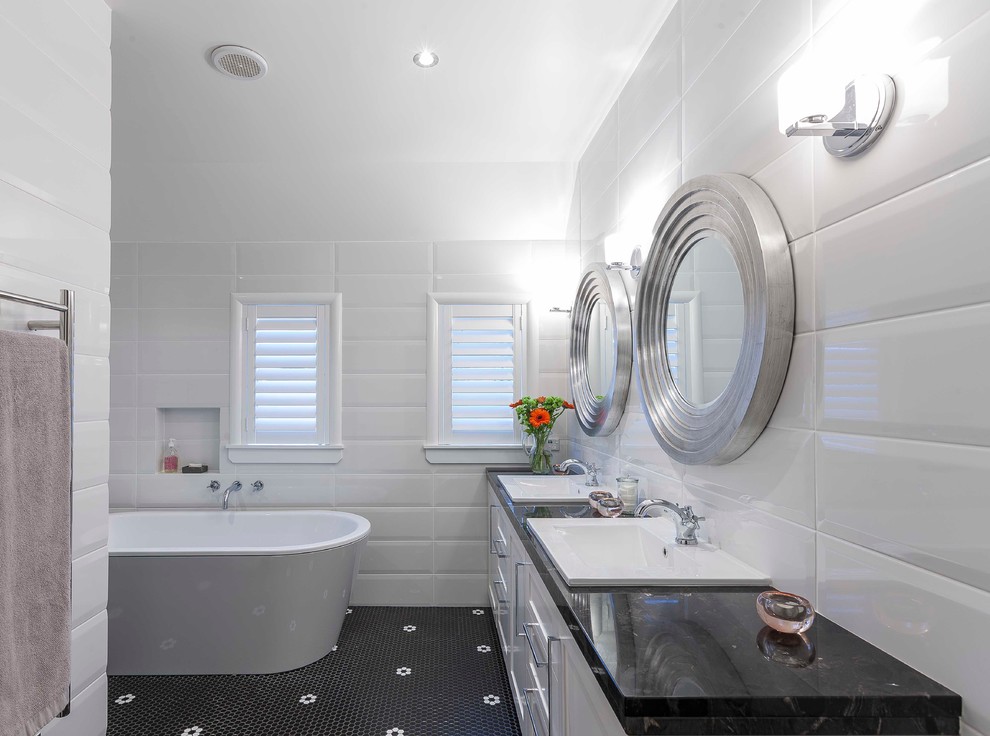 Inspiration for a contemporary bathroom in Auckland with shaker cabinets, white cabinets, a freestanding bath, black tiles, black and white tiles, white tiles, white walls, mosaic tile flooring and a built-in sink.