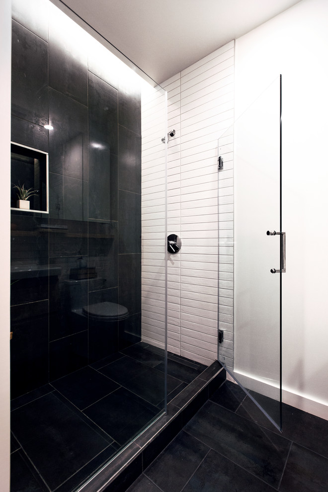 На фото: маленькая главная ванная комната в современном стиле с плоскими фасадами, светлыми деревянными фасадами, душем в нише, унитазом-моноблоком, черно-белой плиткой, керамической плиткой, белыми стенами, полом из сланца, подвесной раковиной, столешницей из искусственного камня, черным полом, душем с распашными дверями и белой столешницей для на участке и в саду с