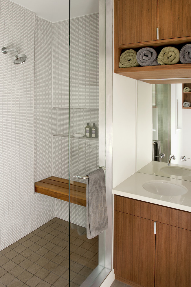 Immagine di una stanza da bagno moderna con lavabo sottopiano, ante lisce, ante in legno scuro, doccia alcova, piastrelle bianche, nicchia e panca da doccia