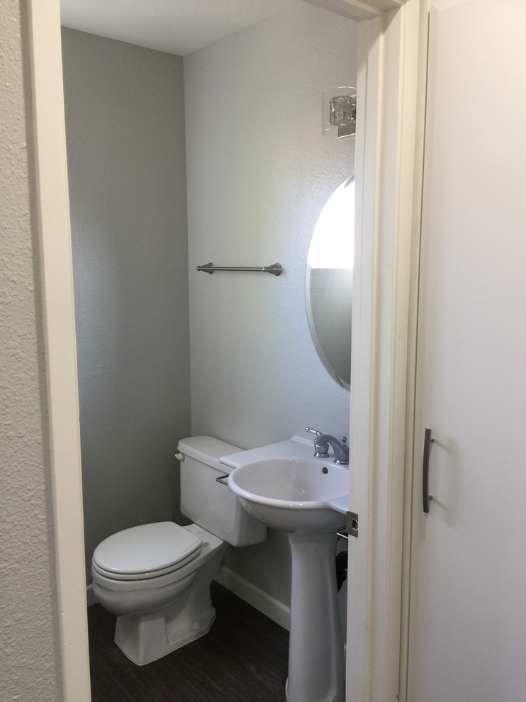 Modern inredning av ett litet badrum, med en toalettstol med separat cisternkåpa, grå väggar, vinylgolv, ett piedestal handfat och grått golv