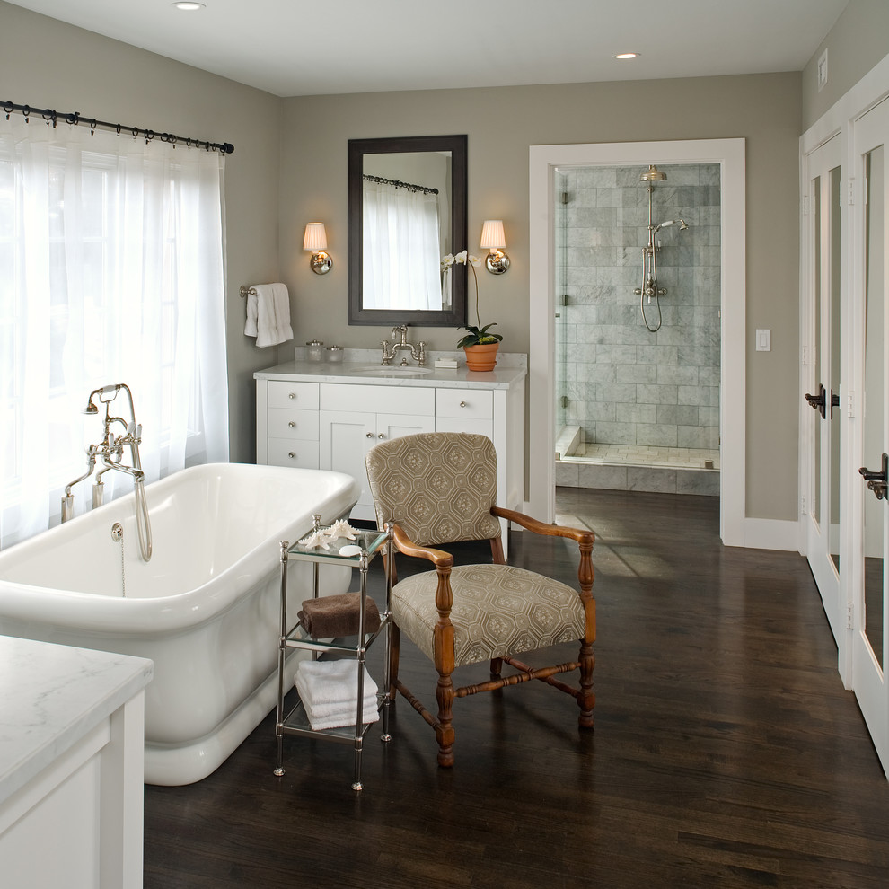 This is an example of a country bathroom in San Diego with a submerged sink, shaker cabinets, white cabinets, a freestanding bath, grey tiles, grey walls and dark hardwood flooring.