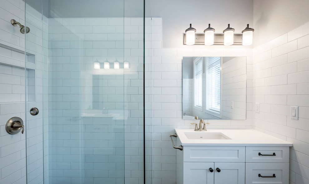 Cette image montre une salle de bain principale traditionnelle de taille moyenne avec un placard à porte shaker, des portes de placard blanches, une baignoire indépendante, WC séparés, un carrelage blanc, un carrelage métro, un mur bleu, un sol en carrelage de céramique, un lavabo encastré, un plan de toilette en quartz, un sol noir, un plan de toilette blanc, une douche d'angle et une cabine de douche à porte coulissante.