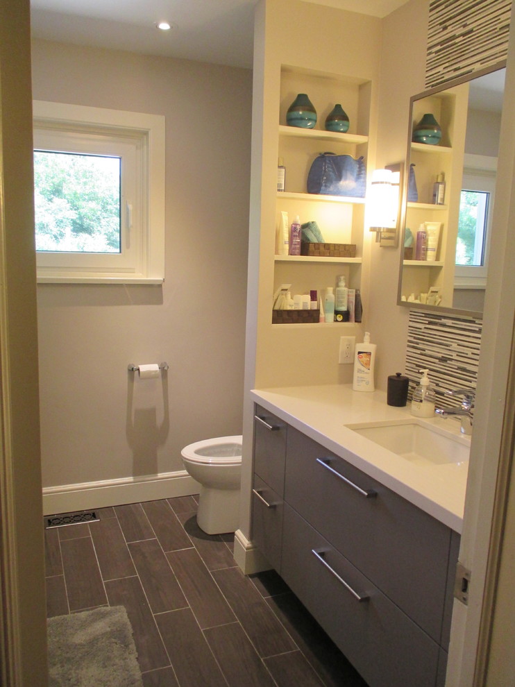 Medium sized contemporary ensuite bathroom in Toronto with a wall-mounted sink, flat-panel cabinets, grey cabinets, quartz worktops, a shower/bath combination, multi-coloured tiles, glass tiles, beige walls and porcelain flooring.