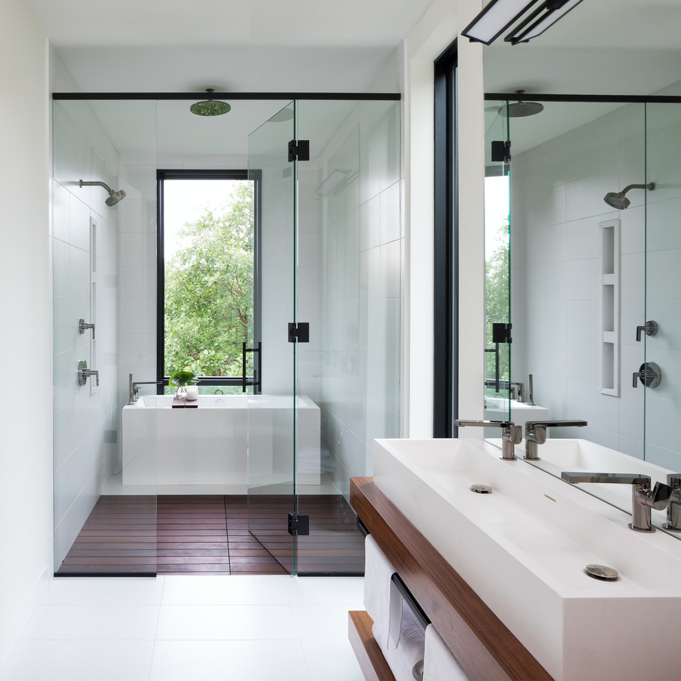 This is an example of a contemporary ensuite wet room bathroom in Minneapolis with open cabinets, a freestanding bath, white tiles, porcelain tiles, white walls, porcelain flooring, white floors, medium wood cabinets, a trough sink, wooden worktops and a hinged door.