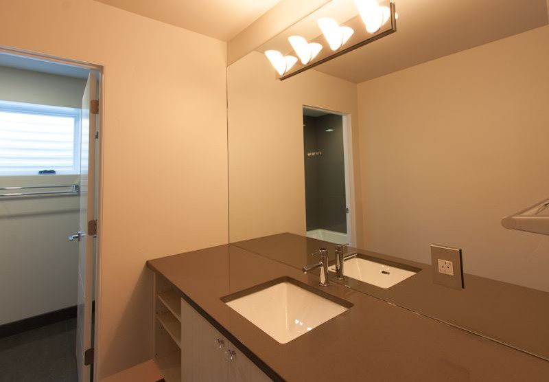 Cette image montre une salle de bain minimaliste de taille moyenne avec un lavabo encastré, un placard à porte plane et un plan de toilette en quartz modifié.