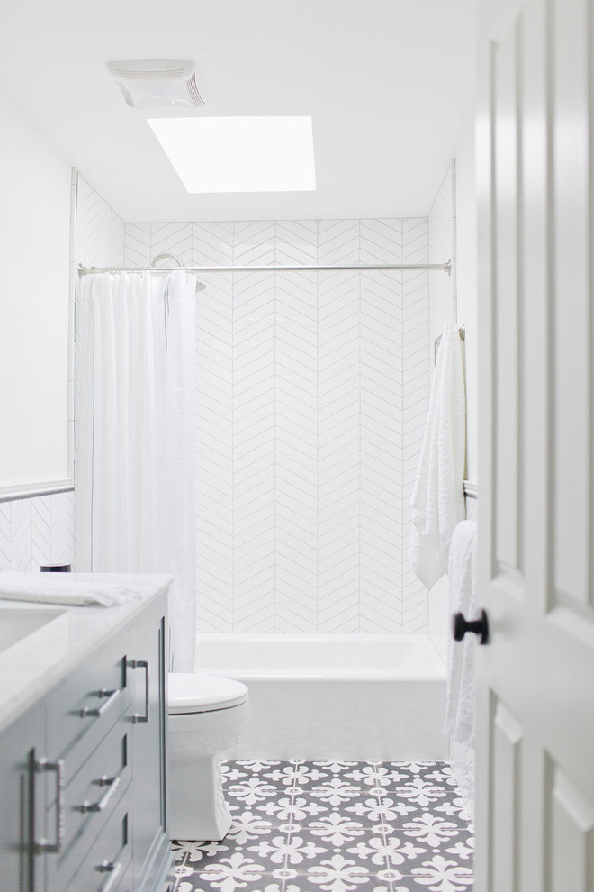 Inspiration för mellanstora klassiska vitt badrum med dusch, med blå skåp, ett badkar i en alkov, en dusch/badkar-kombination, en toalettstol med hel cisternkåpa, vit kakel, porslinskakel, vita väggar, klinkergolv i porslin, ett undermonterad handfat, marmorbänkskiva, flerfärgat golv, dusch med duschdraperi och luckor med infälld panel