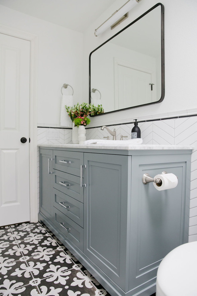 Идея дизайна: ванная комната среднего размера в стиле неоклассика (современная классика) с синими фасадами, ванной в нише, душем над ванной, унитазом-моноблоком, белой плиткой, керамогранитной плиткой, белыми стенами, полом из керамогранита, душевой кабиной, врезной раковиной, мраморной столешницей, разноцветным полом, шторкой для ванной, серой столешницей и фасадами с утопленной филенкой