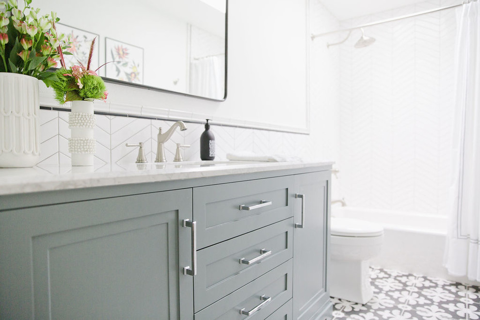 Idéer för ett mellanstort klassiskt grå badrum med dusch, med möbel-liknande, blå skåp, ett badkar i en alkov, en dusch/badkar-kombination, en toalettstol med hel cisternkåpa, vit kakel, porslinskakel, vita väggar, klinkergolv i porslin, ett undermonterad handfat, marmorbänkskiva, flerfärgat golv och dusch med duschdraperi