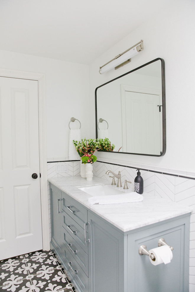Exempel på ett mellanstort klassiskt grå grått badrum med dusch, med möbel-liknande, blå skåp, ett badkar i en alkov, en dusch/badkar-kombination, en toalettstol med hel cisternkåpa, vit kakel, porslinskakel, vita väggar, klinkergolv i porslin, ett undermonterad handfat, marmorbänkskiva, flerfärgat golv och dusch med duschdraperi