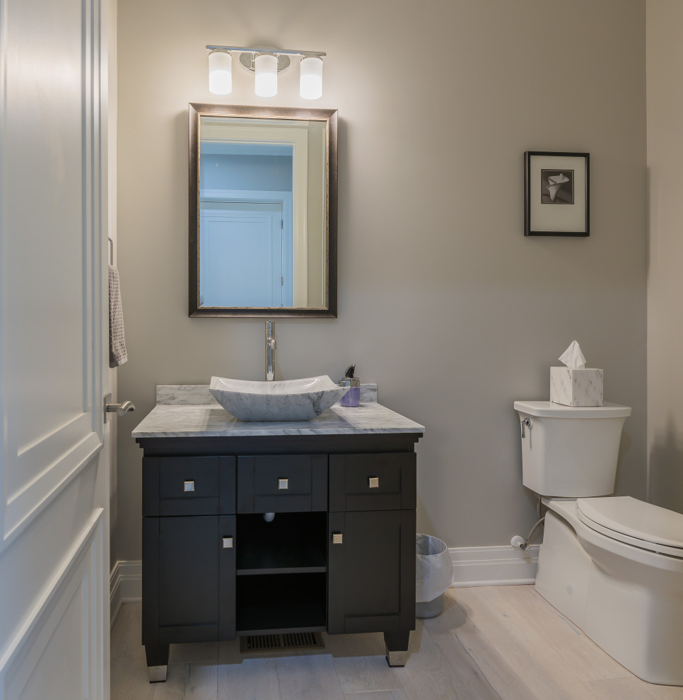 Small traditional bathroom in Atlanta with black cabinets, a two-piece toilet, beige walls, granite worktops, grey floors, multi-coloured worktops, shaker cabinets, light hardwood flooring and a vessel sink.