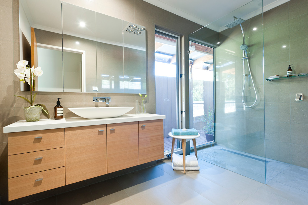 Diseño de cuarto de baño actual con armarios con paneles lisos, puertas de armario de madera clara, ducha a ras de suelo, aseo y ducha y lavabo sobreencimera